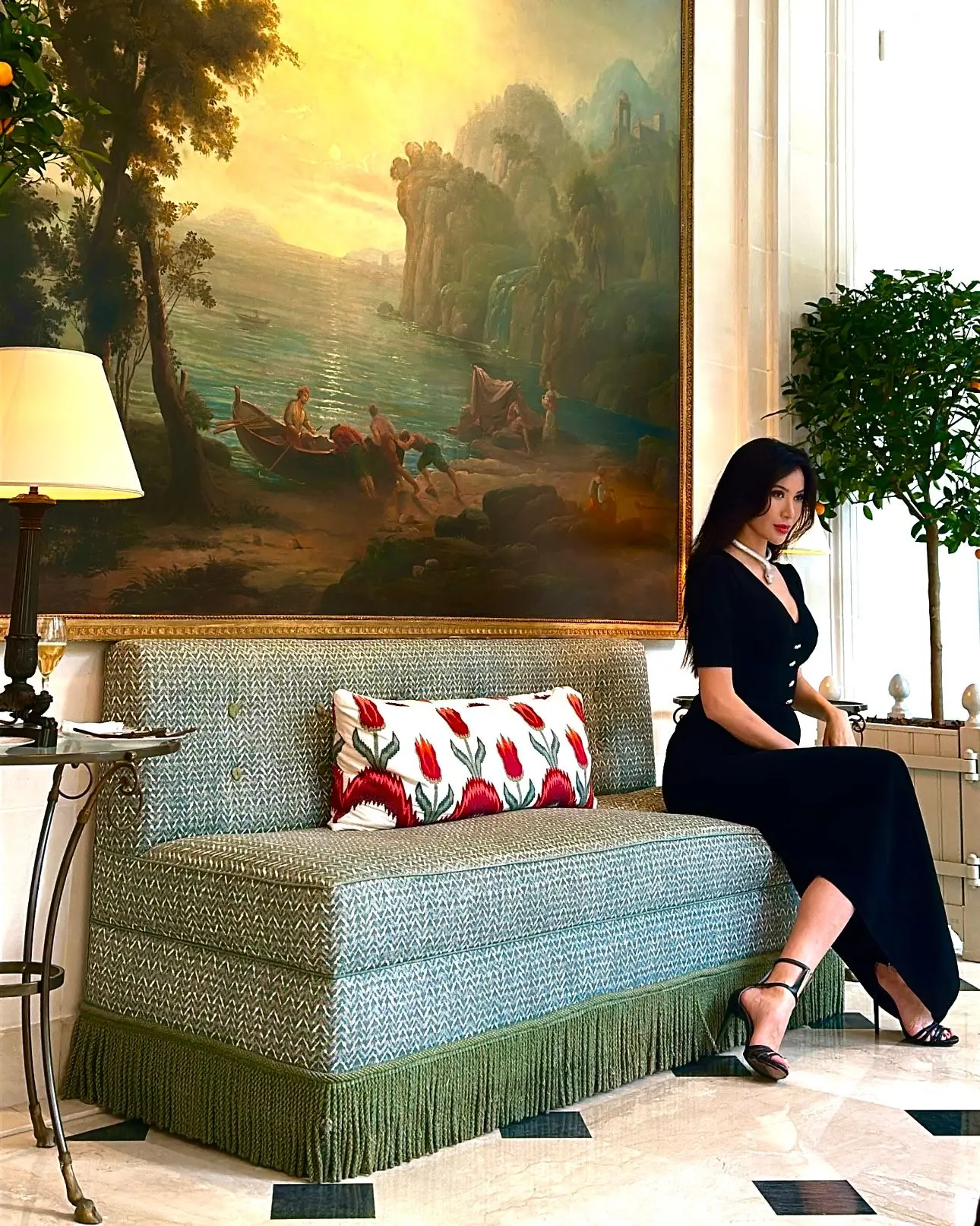 Mannequin en robe noire assise sur une banquette sous un grand tableau